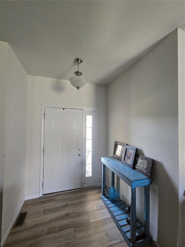 foyer entrance featuring wood finished floors, baseboards, and visible vents