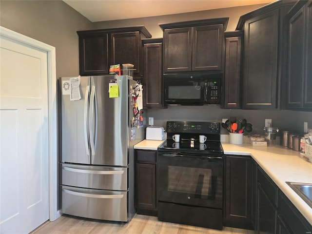 kitchen with light wood-style flooring, light countertops, and black appliances