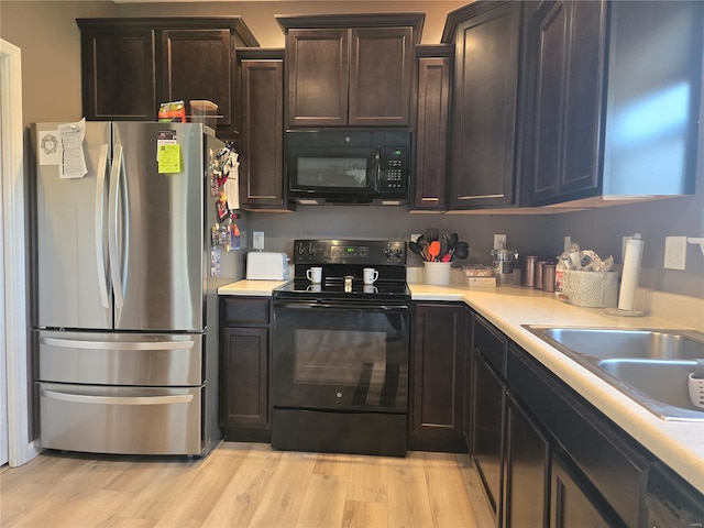 kitchen featuring a sink, light countertops, black appliances, and light wood finished floors