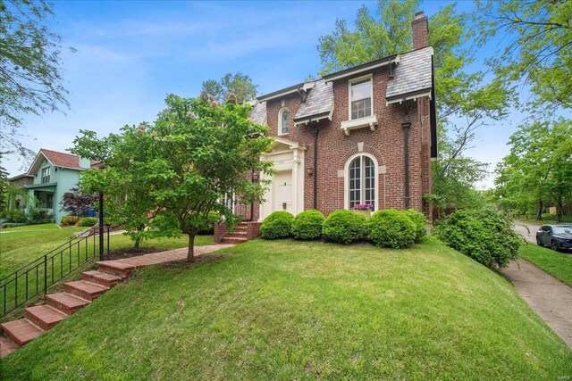 view of front of property with a chimney, a front lawn, and brick siding
