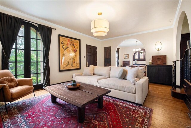 living room with crown molding, arched walkways, a healthy amount of sunlight, and light wood-style floors