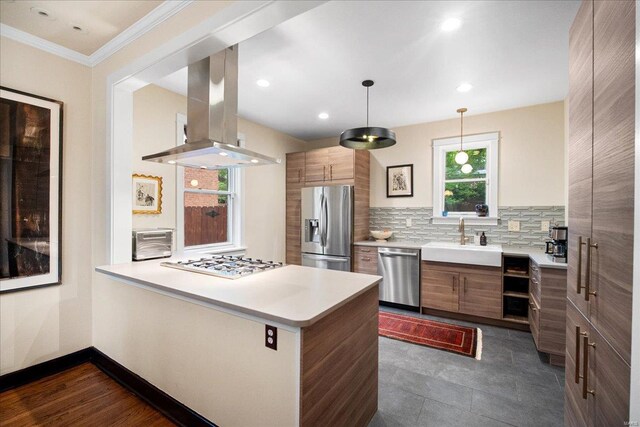 kitchen with a peninsula, light countertops, island exhaust hood, a sink, and appliances with stainless steel finishes