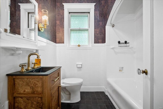 bathroom with vanity, tile patterned flooring, wainscoting, toilet, and tile walls