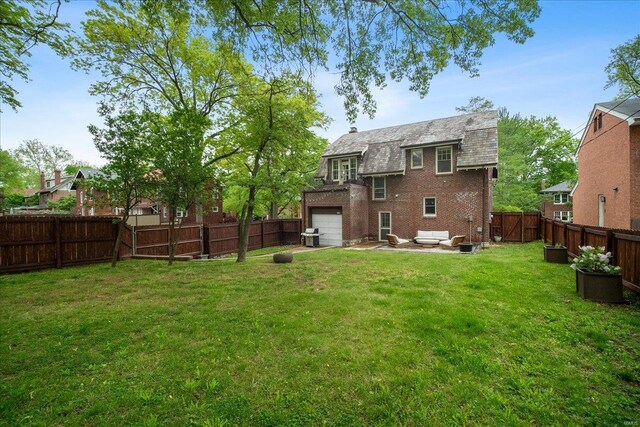 back of house featuring a yard, brick siding, an attached garage, and a fenced backyard