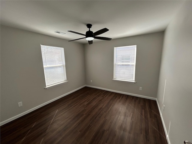 spare room with plenty of natural light, visible vents, dark wood-style flooring, and baseboards