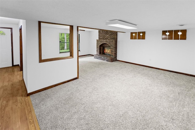 unfurnished living room featuring baseboards, a brick fireplace, and carpet floors