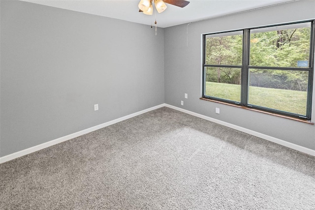 carpeted spare room featuring a ceiling fan and baseboards
