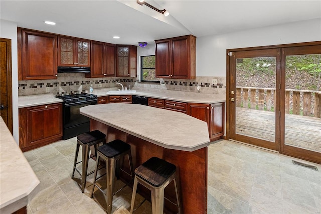 kitchen featuring light countertops, decorative backsplash, under cabinet range hood, and black appliances