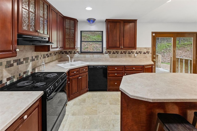 kitchen featuring under cabinet range hood, plenty of natural light, a sink, and black appliances