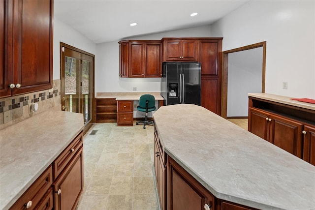 kitchen featuring built in desk, light countertops, recessed lighting, lofted ceiling, and black fridge with ice dispenser