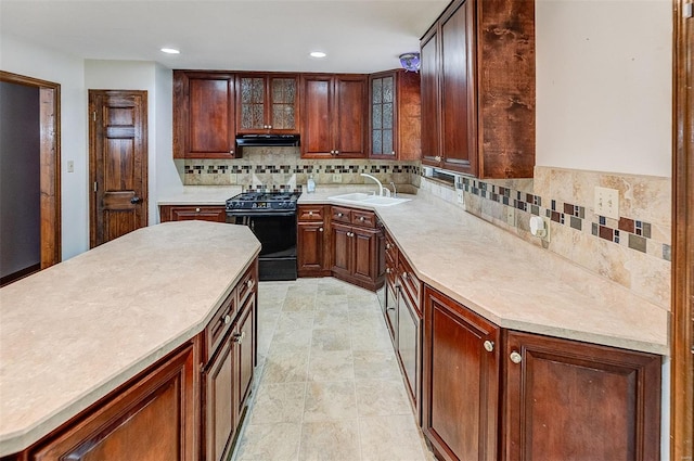 kitchen with a sink, gas stove, light countertops, range hood, and tasteful backsplash