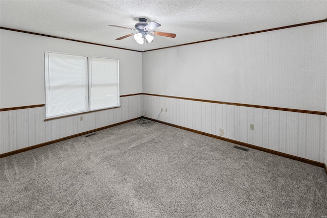 empty room with crown molding, a ceiling fan, carpet floors, and visible vents