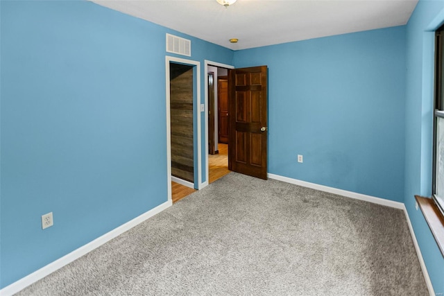 unfurnished bedroom featuring baseboards, carpet, and visible vents