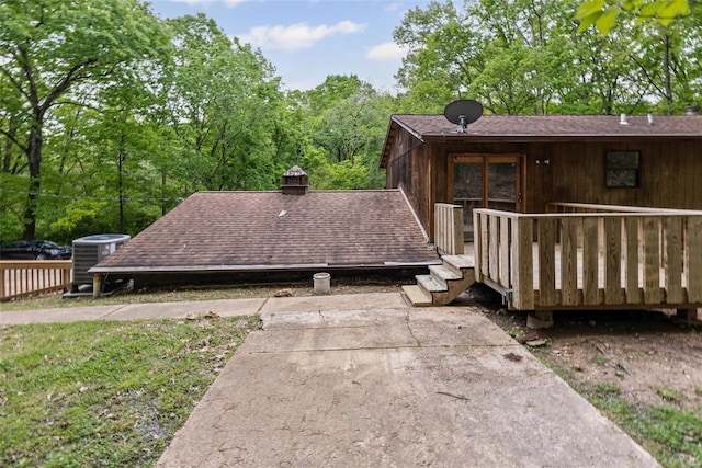 view of side of home featuring roof with shingles, cooling unit, and a deck