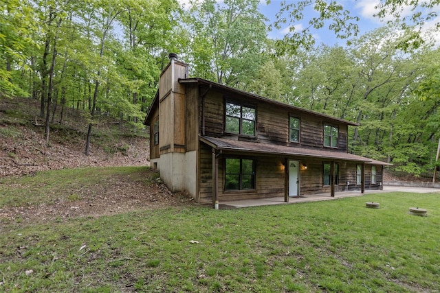 view of front facade featuring a front lawn, a patio area, and a chimney