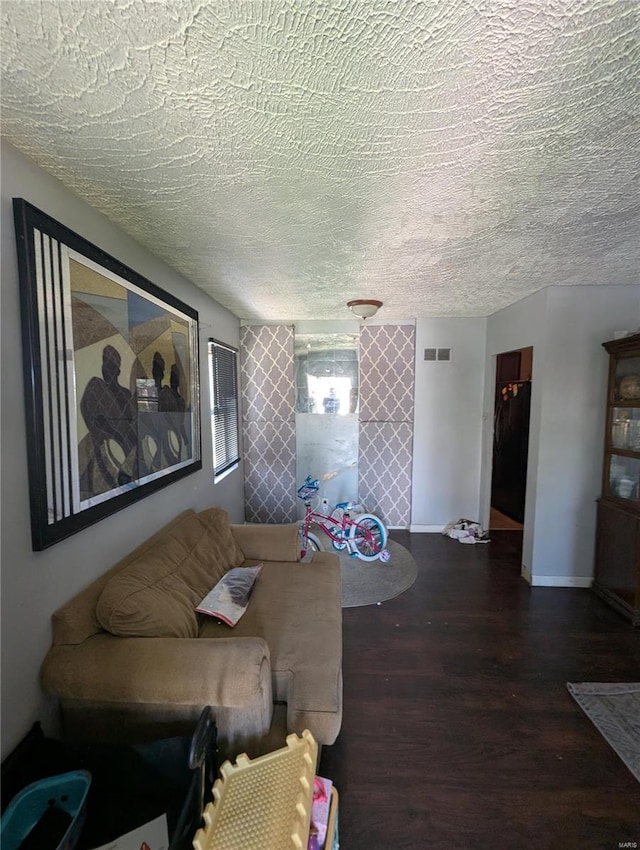 living room featuring visible vents, baseboards, wood finished floors, and a textured ceiling