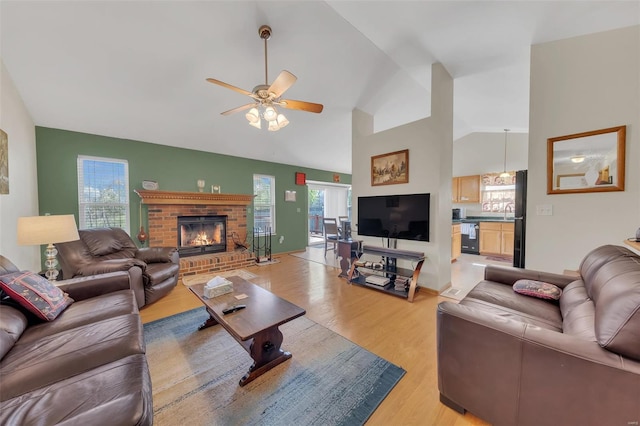 living area featuring light wood-style flooring, ceiling fan, a fireplace, and lofted ceiling