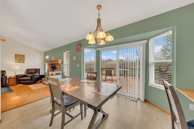 dining space featuring a chandelier, a healthy amount of sunlight, visible vents, and a brick fireplace