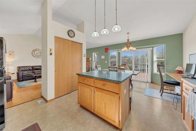 kitchen featuring a notable chandelier, dark countertops, a kitchen island, lofted ceiling, and hanging light fixtures
