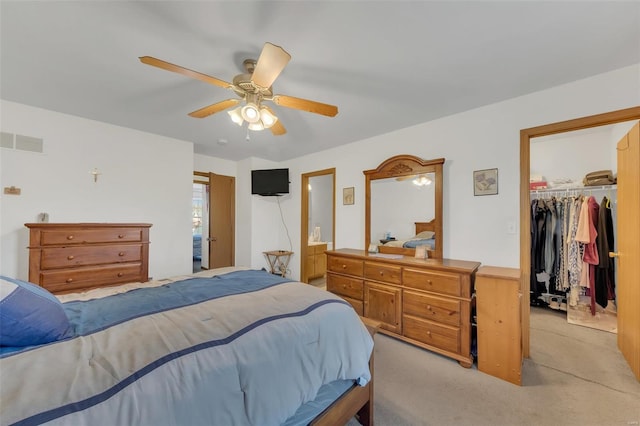 bedroom featuring a ceiling fan, a closet, a walk in closet, light colored carpet, and visible vents