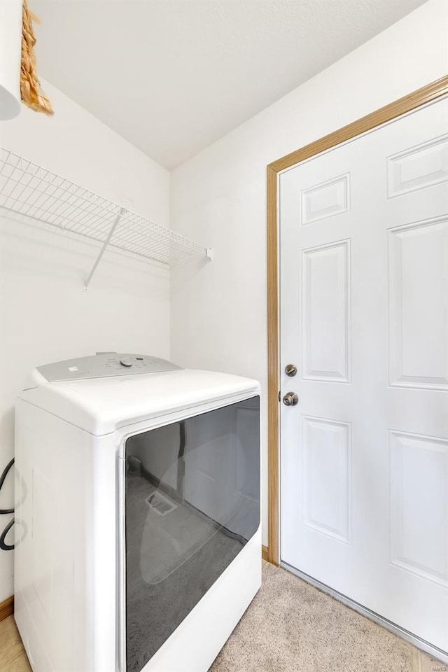 clothes washing area with washing machine and clothes dryer, laundry area, and light carpet