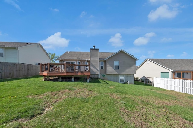 rear view of house with a yard, a fenced backyard, a wooden deck, and a chimney