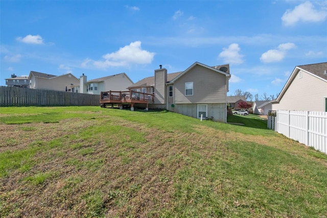 back of house with a residential view, a chimney, a yard, a deck, and fence