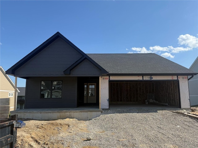 view of front facade featuring an attached garage, a porch, driveway, and french doors