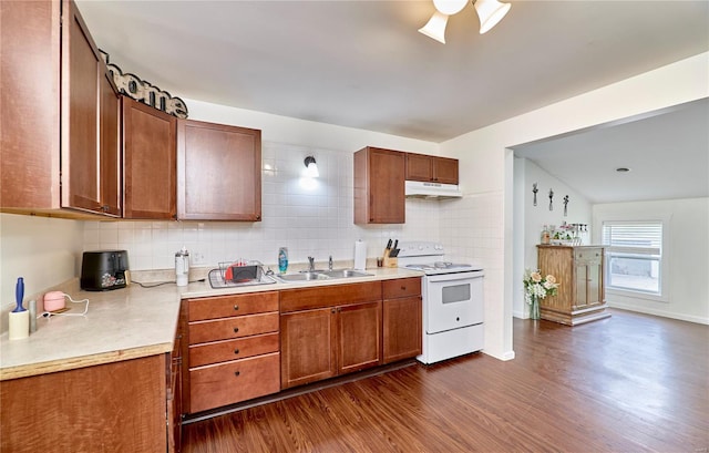 kitchen with a sink, light countertops, under cabinet range hood, dark wood-type flooring, and electric range