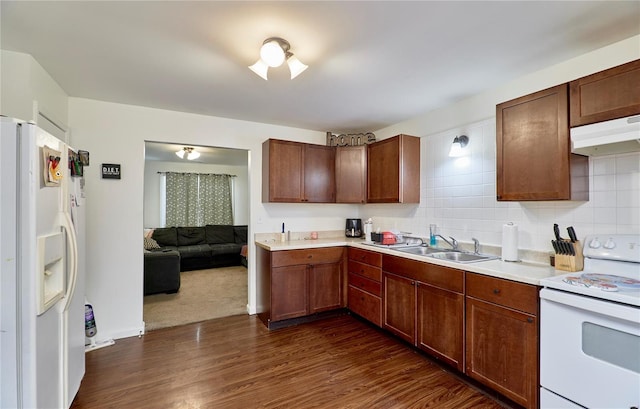 kitchen with a sink, light countertops, white appliances, dark wood-style floors, and under cabinet range hood