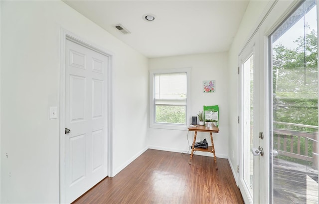 interior space featuring dark wood-style flooring, visible vents, baseboards, and a healthy amount of sunlight