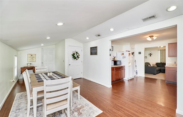 dining space featuring visible vents, baseboards, vaulted ceiling, and dark wood finished floors