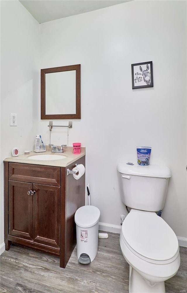 bathroom with toilet, baseboards, vanity, and wood finished floors