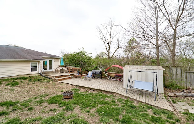 view of yard featuring an outbuilding, a shed, fence, a fire pit, and a deck