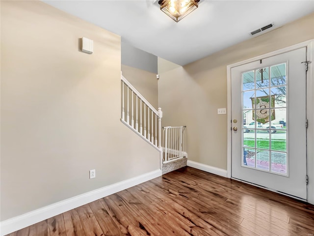 entryway featuring visible vents, baseboards, stairway, and wood finished floors