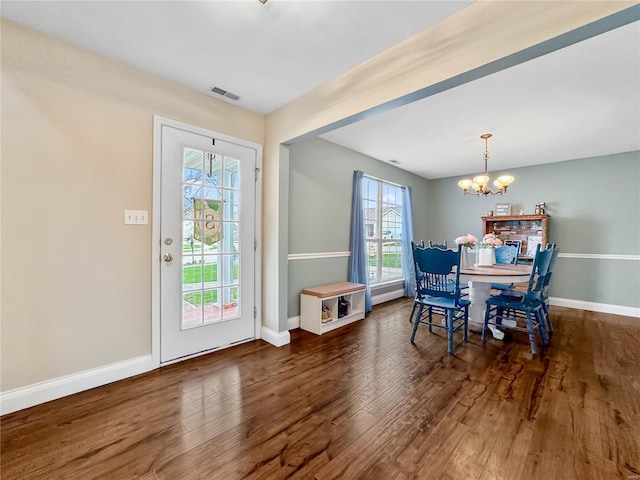 dining area with a notable chandelier, visible vents, baseboards, and wood finished floors