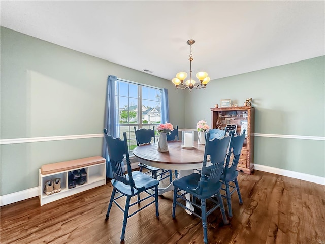 dining space featuring wood finished floors, visible vents, a notable chandelier, and baseboards