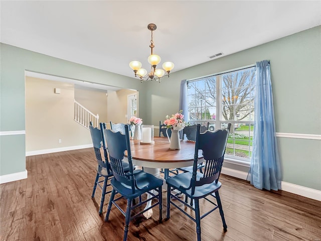 dining area featuring a chandelier, visible vents, baseboards, and wood finished floors