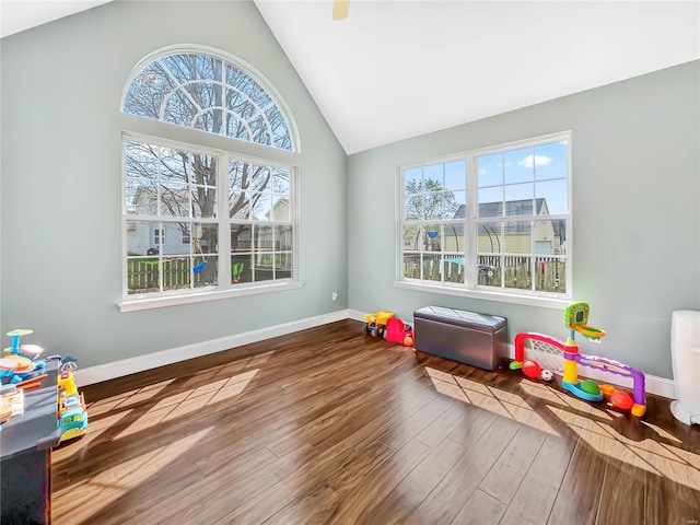 recreation room featuring wood finished floors, high vaulted ceiling, and baseboards