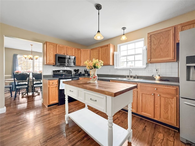 kitchen featuring tasteful backsplash, an inviting chandelier, a sink, stainless steel appliances, and butcher block countertops