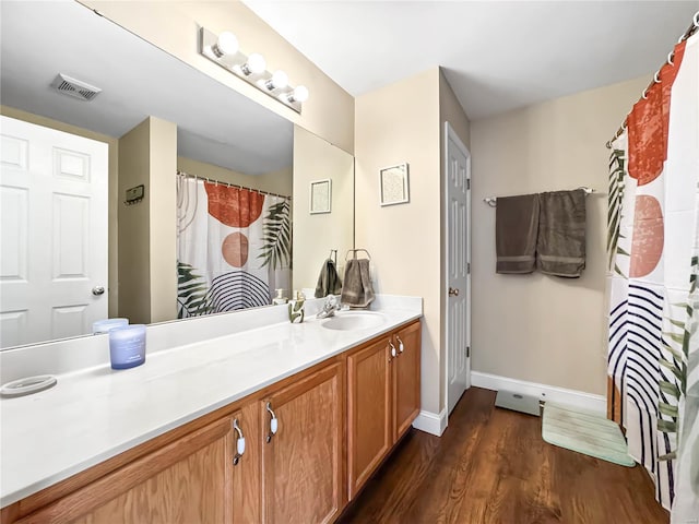 bathroom with vanity, visible vents, baseboards, and wood finished floors
