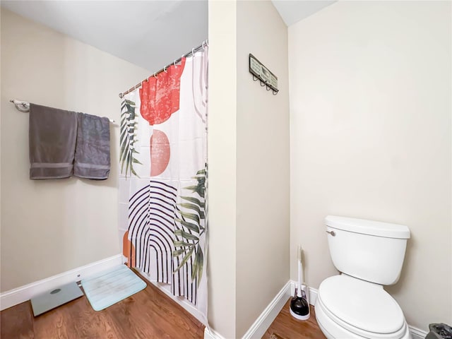 bathroom with toilet, wood finished floors, baseboards, and a shower with shower curtain