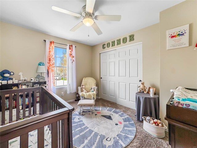 carpeted bedroom with a crib, a closet, and ceiling fan