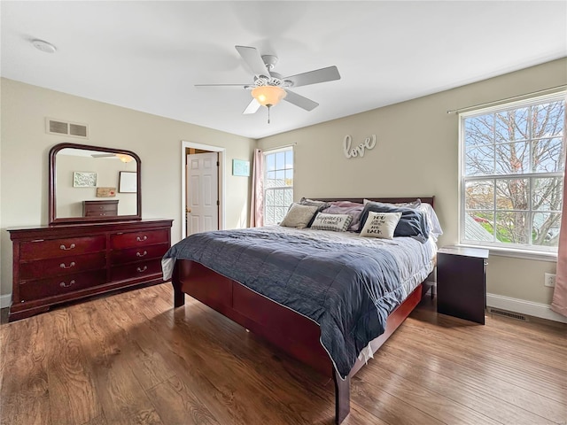 bedroom featuring visible vents, baseboards, a ceiling fan, and wood finished floors