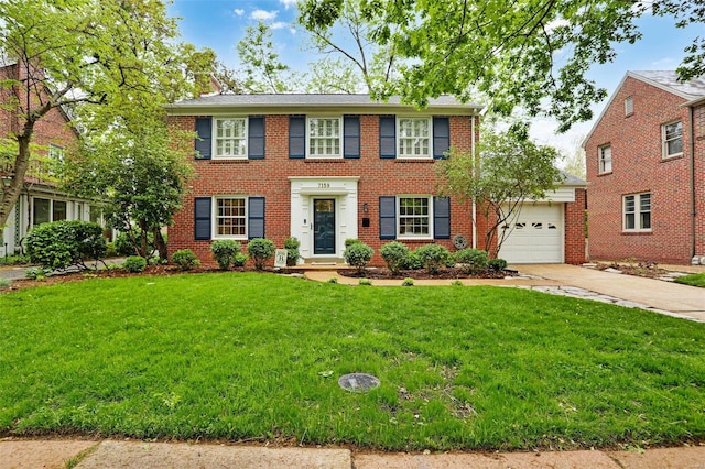 colonial inspired home featuring driveway, a chimney, brick siding, a front lawn, and an attached garage