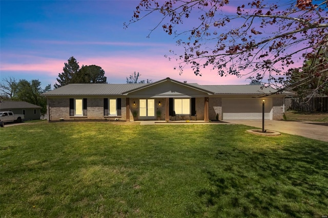 single story home featuring an attached garage, metal roof, brick siding, a front lawn, and driveway