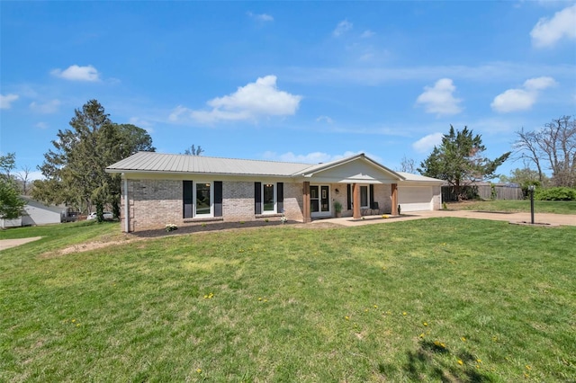 ranch-style house featuring a front yard, an attached garage, metal roof, brick siding, and driveway