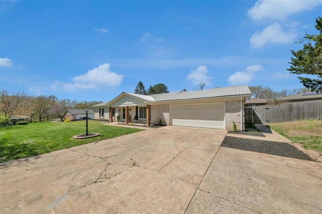 single story home with a front yard, fence, brick siding, an attached garage, and concrete driveway