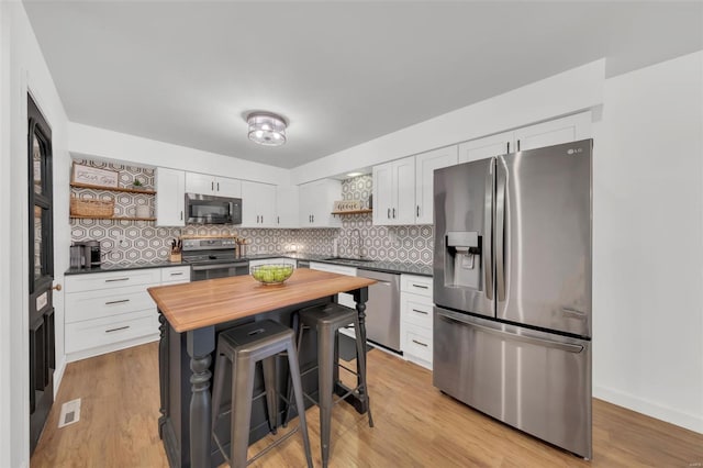kitchen featuring open shelves, butcher block counters, appliances with stainless steel finishes, and decorative backsplash