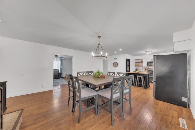 dining room with light wood-style floors, visible vents, and baseboards